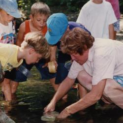 Mary Toohey and students crouched over a stream