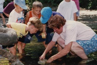 Mary Toohey and students crouched over a stream