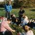 Pat Kelsey and class studying soil, seated on grass in an open field