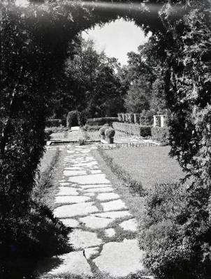 Stone walkway leading from archway into Morton residence gardens