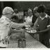 Fish Boil: Volunteer, Marge Clink, serving food behind table to visitors outside Visitor Center