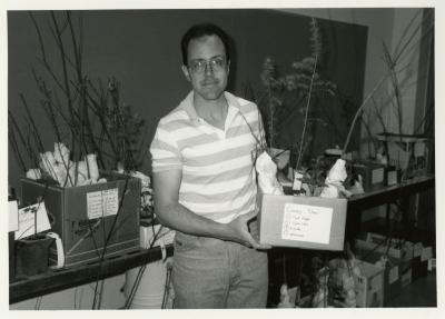 Members' Cooperative Research Program, Mike Spravka holding plant in Research Building basement