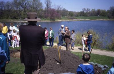 Man with hat looking at crowd listening to tree planting talk given by George Ware on Arbor Day in front of Meadow Lake