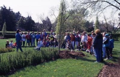 Deb Seymour speaking to crowd, mainly children, at Arbor Day tree planting near Hedge Garden