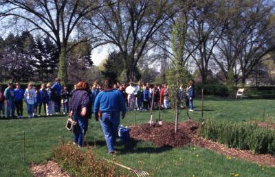Deb Seymour and woman speaking to crowd, mainly children, at Arbor Day tree planting near Hedge Garden