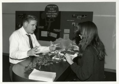 Rose Rieger reviewing plant material with man at Plant Clinic desk