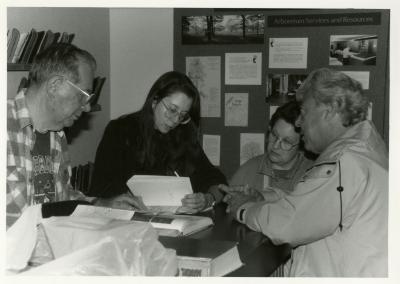 Rose Rieger and man reviewing plant books with man and woman at Plant Clinic desk