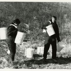 Salt study, Rose Reid and Rick Hootman carrying plastic buckets on berm 