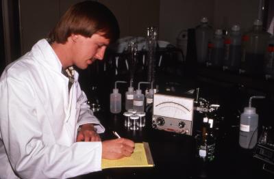 Rick Hootman in lab coat taking notes from chloride analysis of soil extract in lab