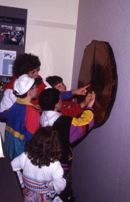 Adult and four children looking at tree rings in Plant Clinic exhibit