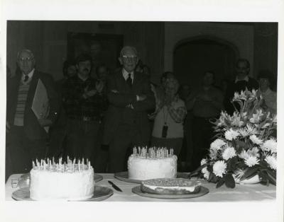 Clarence E. Godshalk's 90th birthday party, standing in front of birthday cakes
