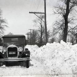 Clarence Godshalk's Model A Ford Roadster on snow covered road, South Farm in background