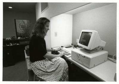 Sterling Morton Library staff, Rita Hassert seated at computer near circulation desk