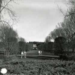 Visitors strolling through Hedge Garden with Four Columns in distance
