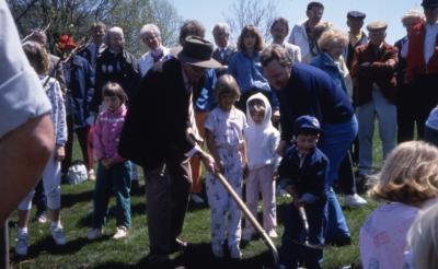 Crowd with two adults and three children planting tree on Arbor Day