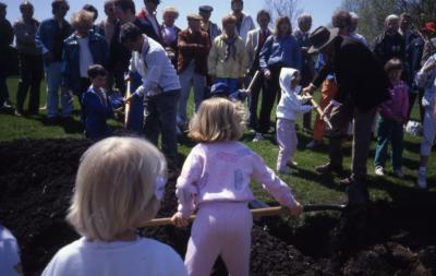 Crowd with little girl in pink and other children planting tree on Arbor Day