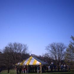 View of crowd in yellow tent near berm on Earth Day