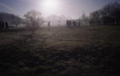 Morning sun in mist over crowd gathering for Earth Day tree planting