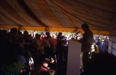 Joe Larkin in tent speaking to large crowd on Earth Day