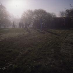 Sun in morning mist with crowd gathering for Earth Day tree planting
