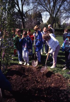 Adults and children with shovels at Arbor Day tree planting