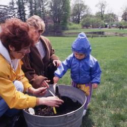 Susan Klatt helping toddler plant tree seedling during Arbor Week celebration