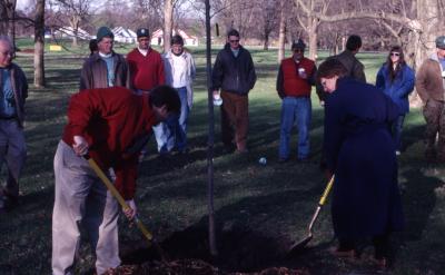 Kris Bachtell and Patti Jelen shoveling soil over newly planted tree at Arbor Day employee tree planting