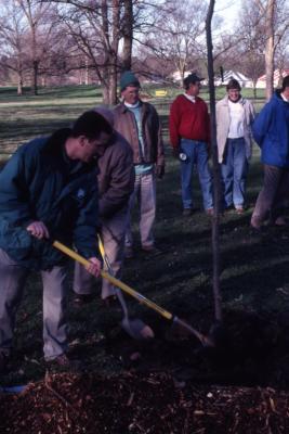 Scott Moberg shoveling soil over newly planted tree at Arbor Day employee tree planting