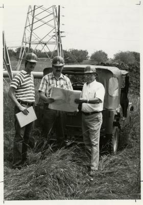 Rick Hootman (left), Pat Kelsey, and George Ware (right) in hard hats studying contour maps for future site of Crabapple Lake