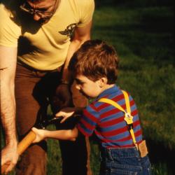 Man holding shovel with young boy during Earth Day celebration and berm planting
