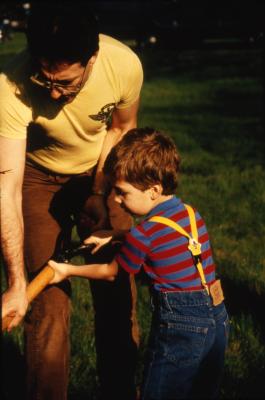 Man holding shovel with young boy during Earth Day celebration and berm planting