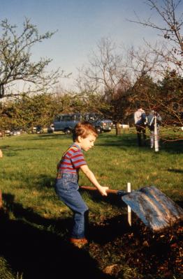 Small boy with big shovel turning over soil during Earth Day celebration and berm planting