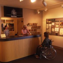 Web Crowley and Chris Martner assisting visitor in wheelchair at Plant Clinic desk