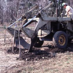 Doug Monroe driving tractor with blade attached to the front, used for transplanting trees, digging up tree from ground