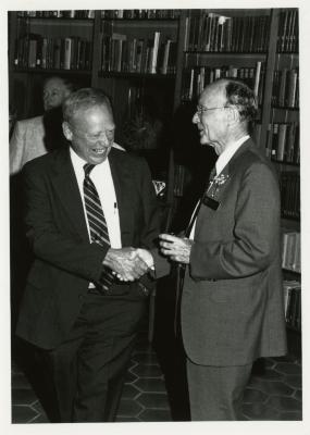 Dr. Marion Hall and Charles Haffner III shaking hands at party in Library