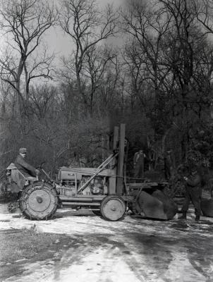 Clarence Godshalk driving Arboretum's first international tractor with front end loader carrying tree