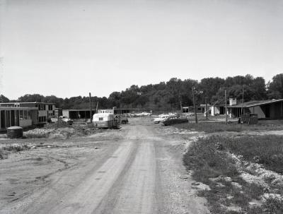 Arbordale houses under construction, unpaved road leading up to development with cars parked