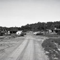 Arbordale houses under construction, unpaved road leading up to development with cars parked