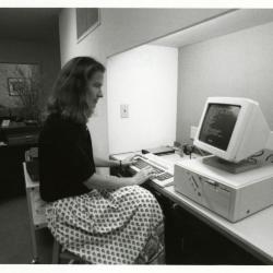 Sterling Morton Library staff, Rita Hassert seated at computer near circulation desk