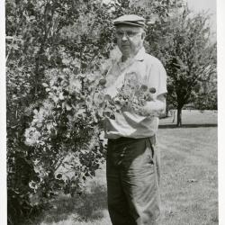 Roy Nordine outdoors holding branch of plant