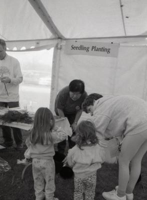 Arbor Day activities at The Morton Arboretum. Tom Simpson (left) and Heidi Tamanaha, volunteer, helping two girls and woman at Seedling Planting station