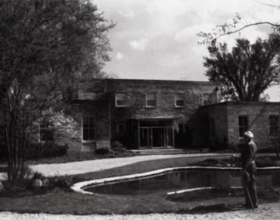 Administration Building with new front entrance, man standing next lily pond