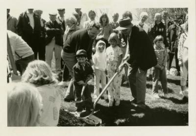 Arbor Day, two men and three children planting tree with surrounding crowd