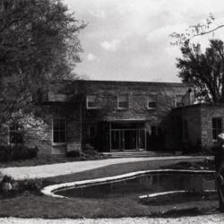 Administration Building with new front entrance, man standing next lily pond